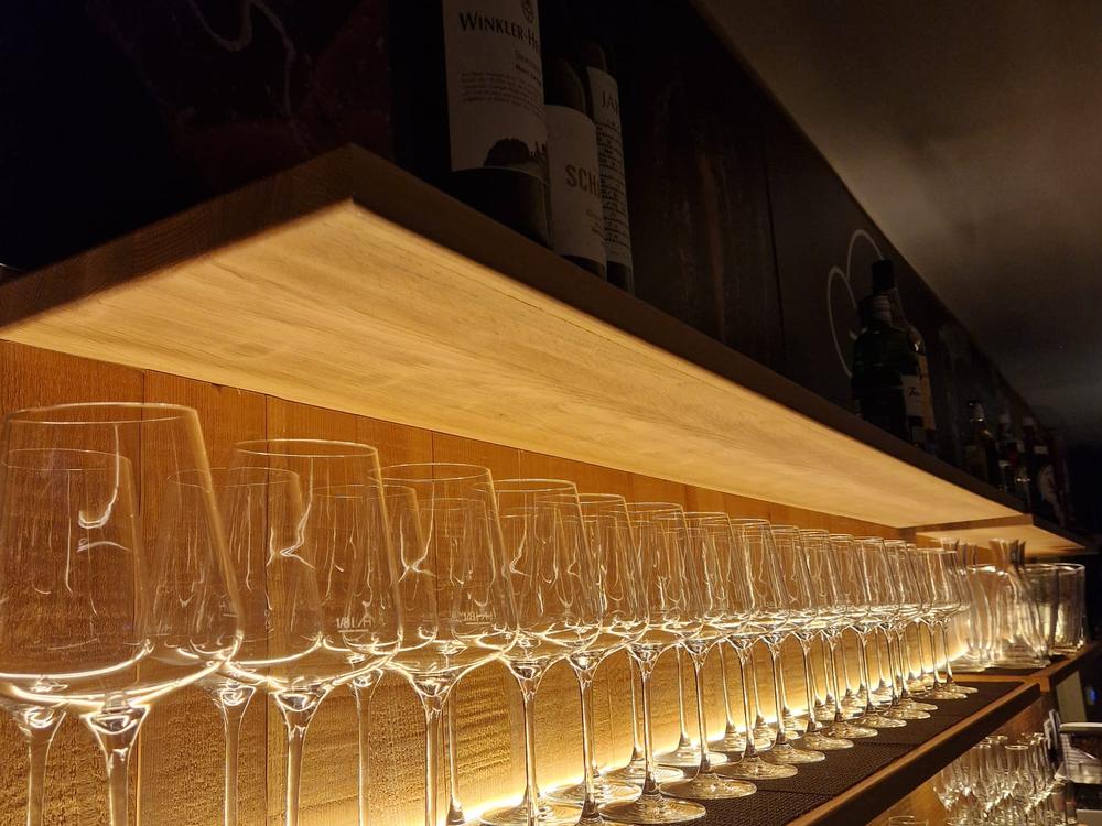 Reihe polierter Gläser an der Bar im warmen Licht