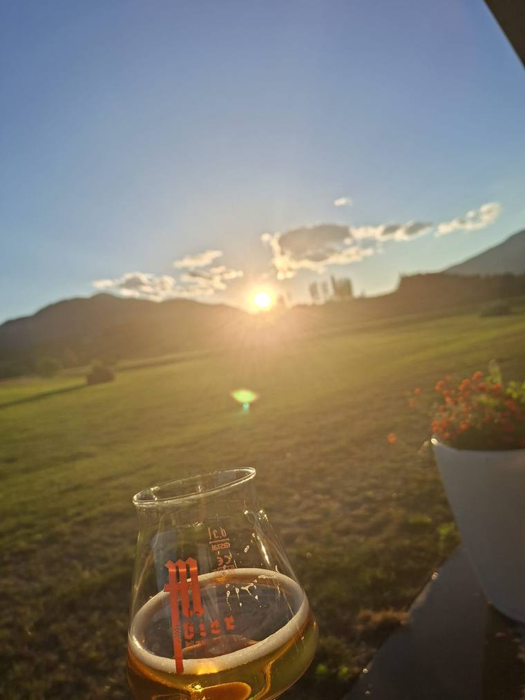 Glas Bier vor der untergehenden Sonne über den Wiesen